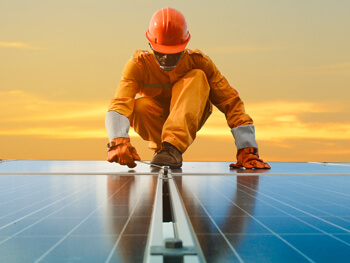 Technician in safety gear working on a solar panel