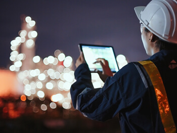 Technician in safety gear reviewing a tablet