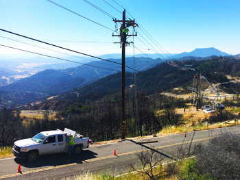 Ardent work vehicle parked along a rode with power lines in the background