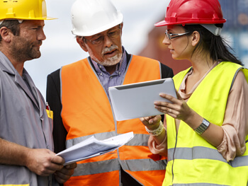 Three project managers discussing a project wearing safety gear